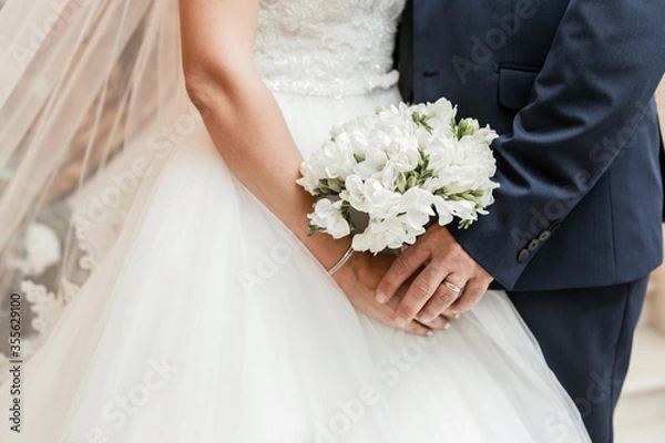 Fototapeta the bride and groom are holding a wedding bouquet. white roses for the holiday