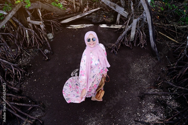 Fototapeta Muslim woman standing on black sand beach in holiday, Asian tourist walking on dark background.