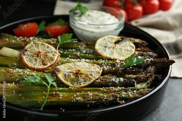 Fototapeta Oven baked asparagus with lemon slices served on plate, closeup