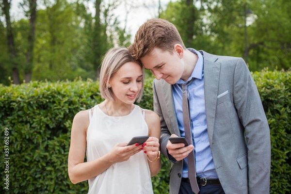 Fototapeta Happy couple using smartphone and laughing outdoor