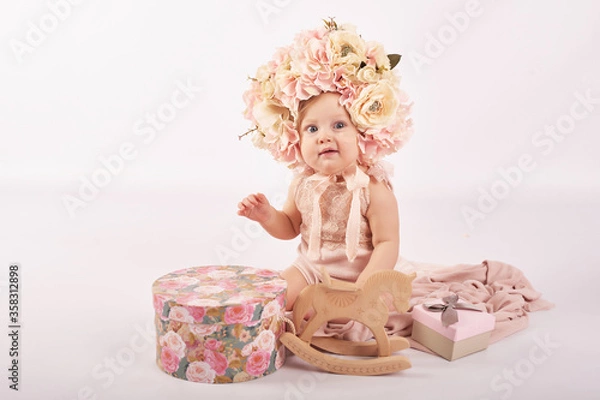 Fototapeta Sweet funny baby in hat with flowers. Easter greeting card, copyspace for your text. Poster for Easter holiday. Congratulations on Mother's Day. Cute baby girl. Children Protection Day