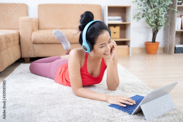 Fototapeta Asian woman See how to exercise from the tablet. She is resting and listening to music.