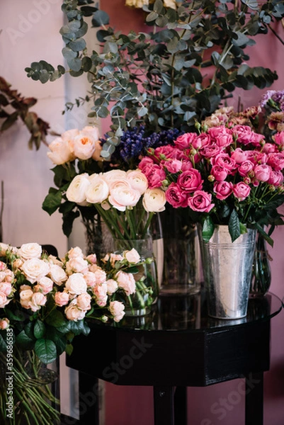 Fototapeta Fresh delivery at the florist shop: vases with blossoming roses, eucalyptus, carnations, ranunculus flowers 