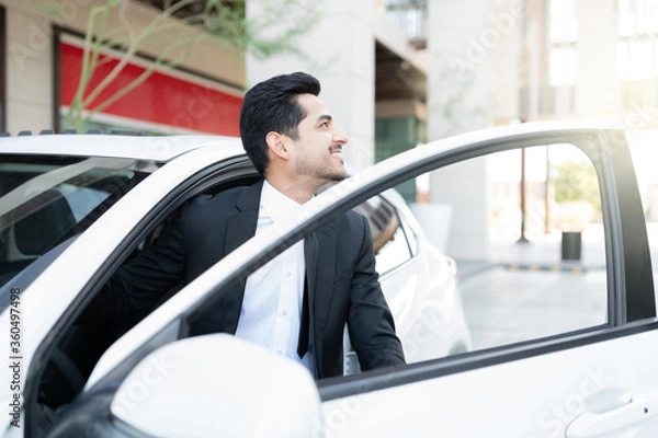 Fototapeta Smiling Male Executive Getting Out From Car