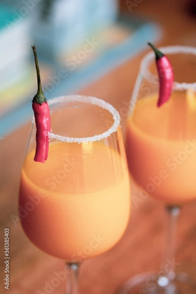 Fototapeta Top down view of cocktail glasses with orange, mango and red chilli exotic drinks in a British summer home garden. 