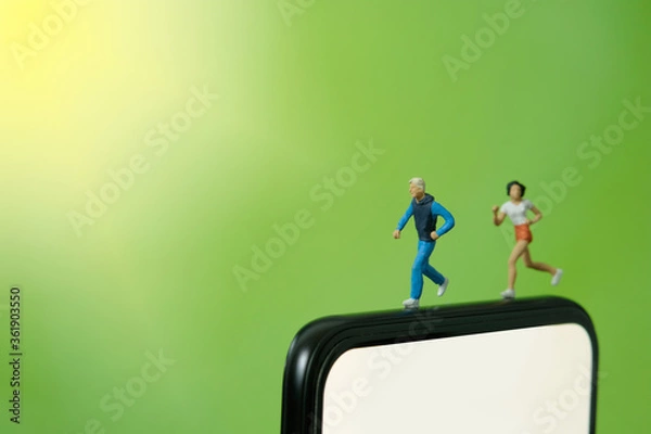 Fototapeta Running and jogging tracking app concept. A men and women running above smartphone. Miniature people figure photography.