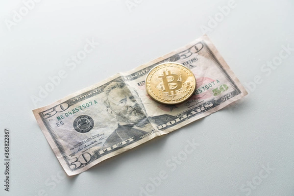 Fototapeta Biktcoin coin lies on paper dollar banknotes. Concept of virtual currency in exchange