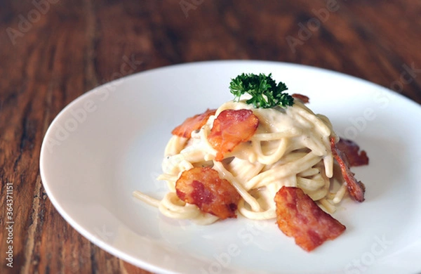 Fototapeta Delicious spaghetti carbonara with bacon on wooden table