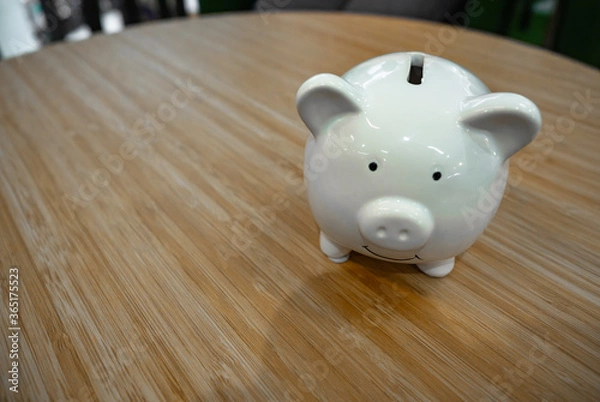 Fototapeta Piggy bank standing on wooden table. copy space for commercial. saving money is investment concept.