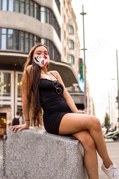 Fototapeta Young hispanic woman posing on a summer day while strolling through a square