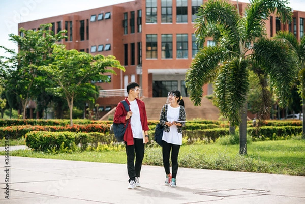 Fototapeta Male and female students wear a face Chill and stand in front of the university.