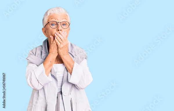 Fototapeta Senior beautiful woman with blue eyes and grey hair wearing casual clothes and glasses shocked covering mouth with hands for mistake. secret concept.