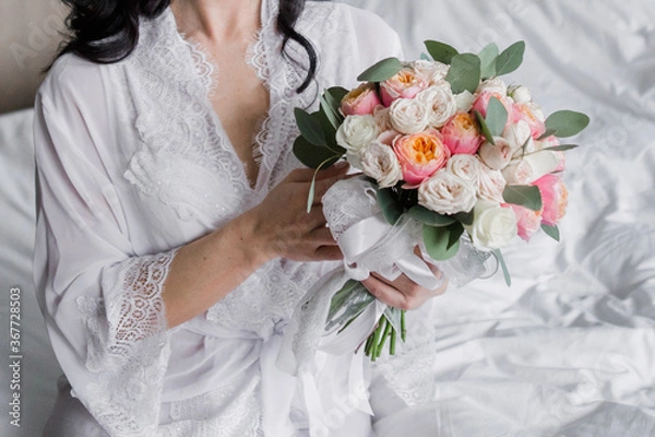 Fototapeta a woman in a peignoir sits on a bed at a wedding