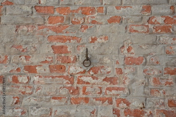 Fototapeta Metal hook on old brick wall with fallen off plaster