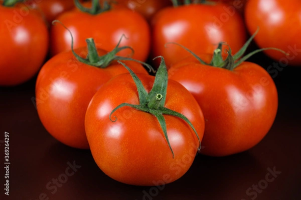 Fototapeta Mehrere leuchtend rote Tomaten - saftig und frisch auf einem schwarzen Hintergrund