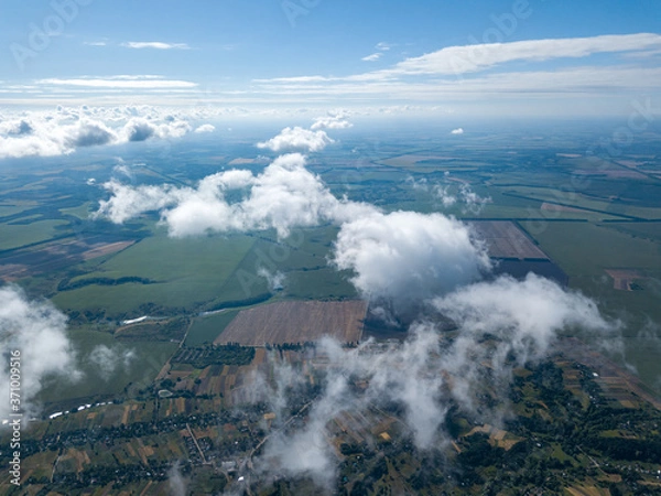 Fototapeta High flight in the clouds over agricultural fields.