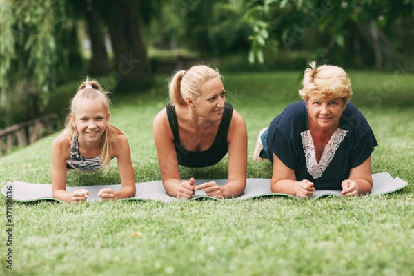 Fototapeta Grandmother, mom and child are doing fitness together in nature. Go in for sports. Healthy lifestyle