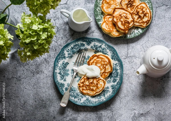 Fototapeta Morning breakfast table - apples pancakes with sour cream, teapot, bouquet of hydrangeas on a gray background, top view