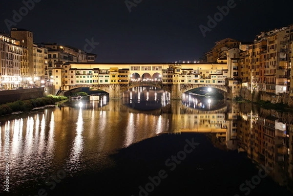 Fototapeta Ponte Vecchio over Arno River panorama in Florence Italy at night.