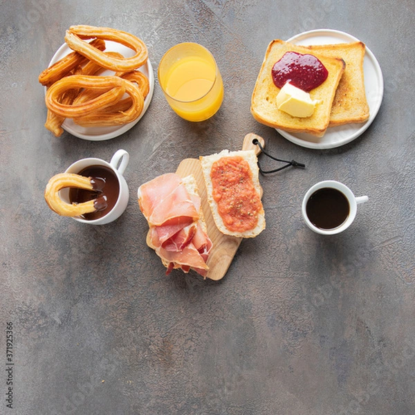 Fototapeta Typical Spanish breakfast concept. Tortilla, bruschetta with jamon and tomatoes, churros with chocolate,  crusty toast with butter and jam ,coffee and orange juice.