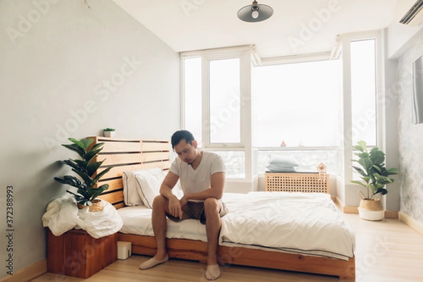 Obraz Lonely and depressed Asian man in his bedroom in the apartment.