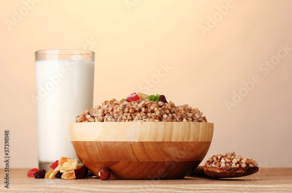 Fototapeta Boiled buckwheat in a wooden bowl with a glass of milk