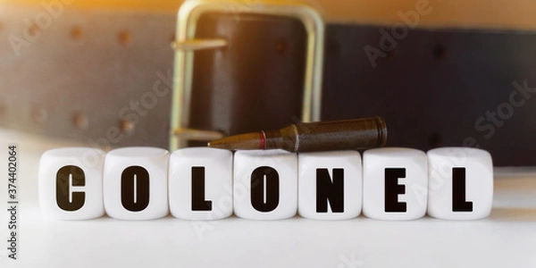 Fototapeta Against the background of a cartridge and a military belt, cubes with the inscription - COLONEL