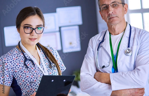 Fototapeta A medical team of doctors, man and woman,standing in office