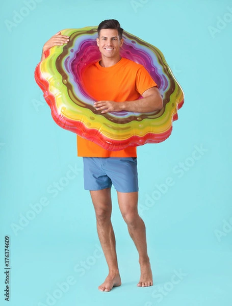 Fototapeta Young man with inflatable ring on color background