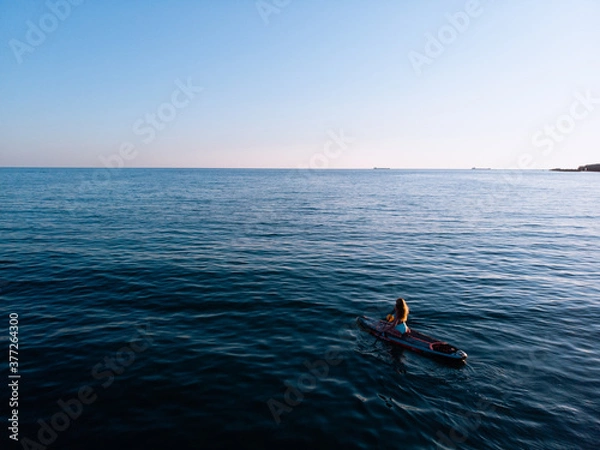 Fototapeta Attractive Woman on Stand Up Paddle Board, Woman paddling on sup board and enjoying turquoise transparent water. Tropical travel, wanderlust and water activity concept. Sunset and relax