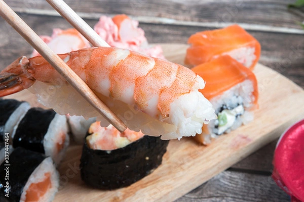 Fototapeta Hand holding sushi with chopsticks