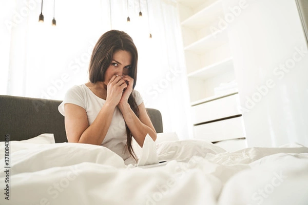 Fototapeta Long-haired Caucasian woman blowing her nose indoors