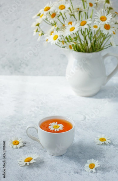 Fototapeta a Cup of tea with chamomile and a bouquet of daisies in a vase. still life bouquet of field daisies in a vase,  and a cup of tea on a white background