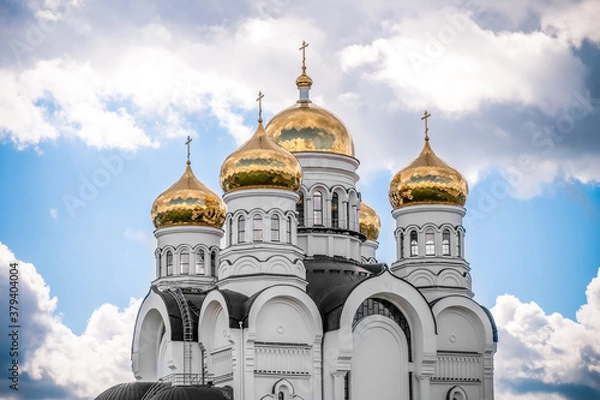 Fototapeta Golden domes, cupolas with Eastern Orthodox crosses on a white Church against a blue sky with clouds