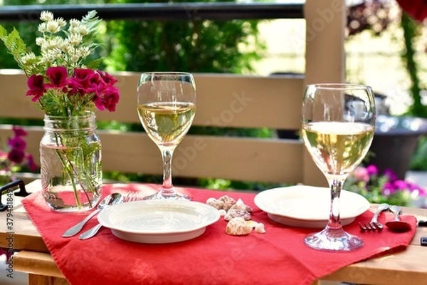 Fototapeta Outdoor al fresco patio table with beautiful place settings for relaxing dining on a warm summer evening 