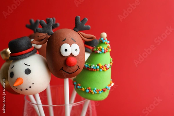 Fototapeta Delicious Christmas themed cake pops on red background, closeup