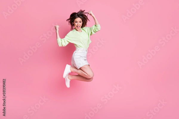 Fototapeta Full body profile photo of attractive crazy lady jump up celebrate great win raise fists wear casual green crop pullover naked belly jeans short skirt shoes isolated pink color background