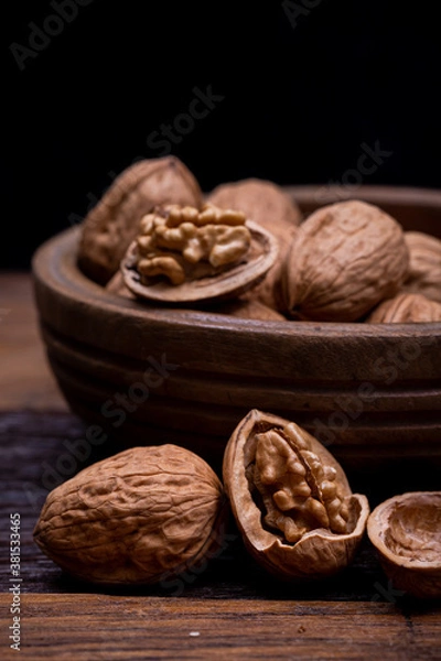 Fototapeta still life with Walnut kernels and whole walnuts on rustic old wooden table.