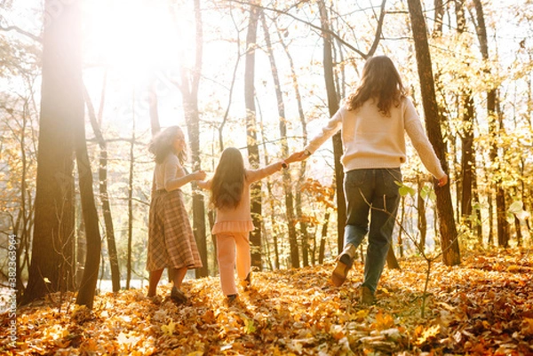 Fototapeta The homosexual family playing with her daughter in the autumn forest. The adventure is more fun when they are together. Autumn women.