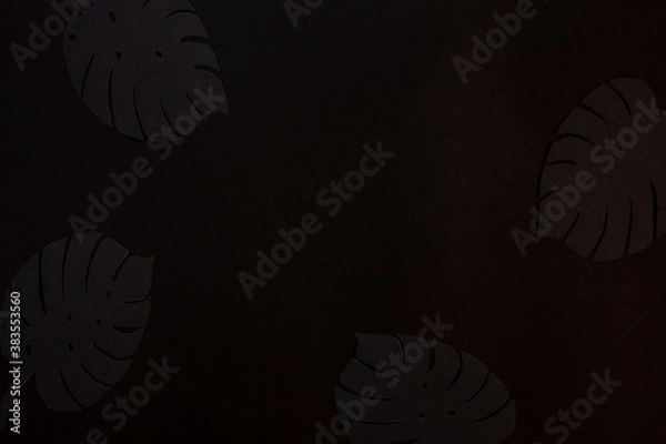 Fototapeta Close up photo of Black paper cut background.  Realistic tropical plant leaves shape paper cut decoration.  Black on Black