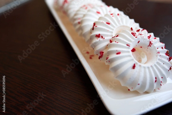 Fototapeta White meringue cakes with red pastry crumb sprinkles. Close-up. Selective focus