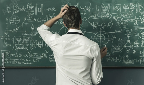 Fototapeta Mathematician solving problems and writing formulas on the chalkboard