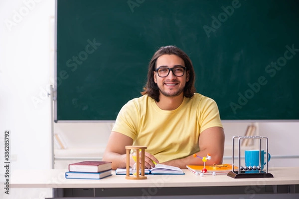 Fototapeta Young male student physicist preparing for exams in the classroo