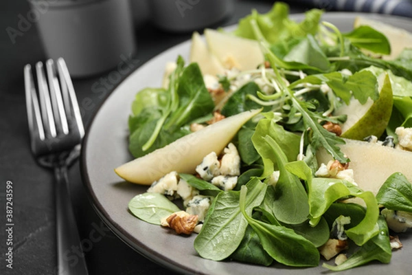 Fototapeta Tasty salad with pear slices and fork on black table, closeup