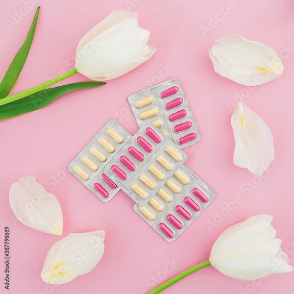 Fototapeta Medical concept with vitamins pills and white flowers on pink background. Flat lay