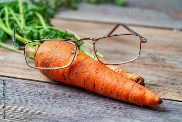 Fototapeta Glasses lie on fresh carrots. Effect of carrots on human eyesight