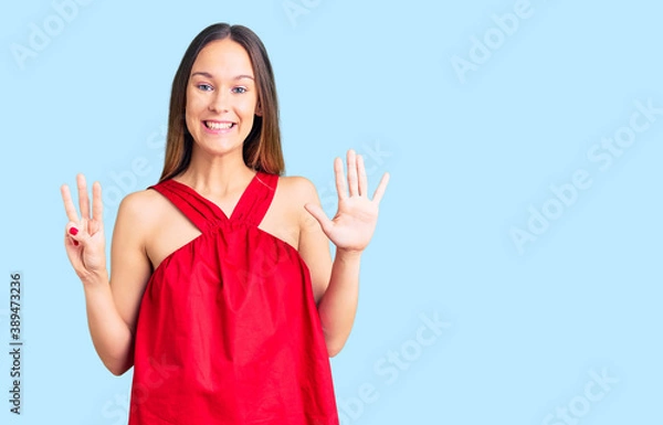 Fototapeta Beautiful brunette young woman wearing casual clothes showing and pointing up with fingers number eight while smiling confident and happy.