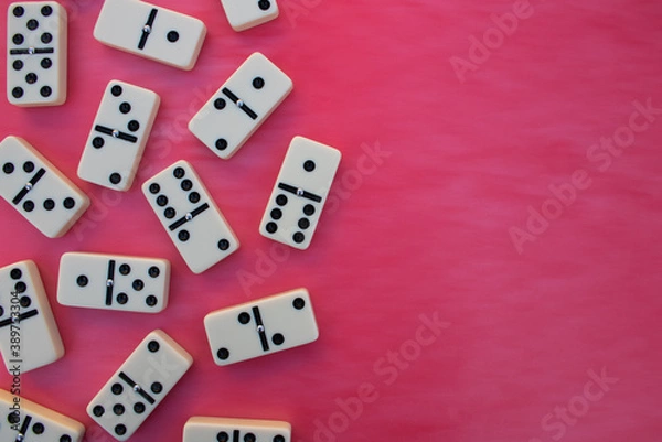 Fototapeta Deck of scattered dominoes on vibrant red background. Top down view flat lay with empty space for text