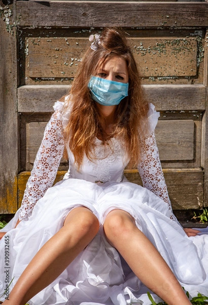 Fototapeta sad young bride in white dress during pandemic