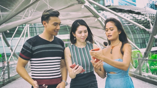 Fototapeta Three asian young friends enjoy outdoor time visiting a new city